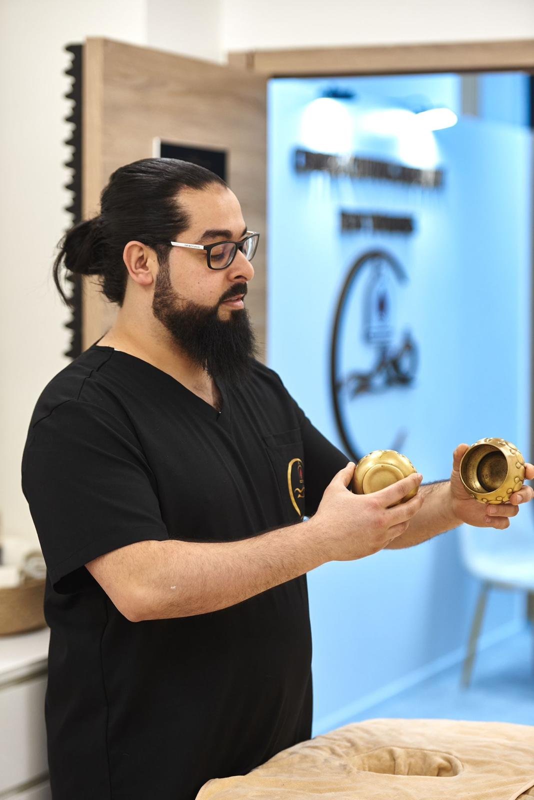 Ben Younes tenant des ventouses en cuivre dans la salle de soin du centre